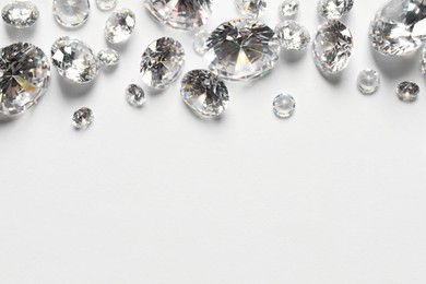 Photo of Many beautiful shiny diamonds on white background, flat lay. Space for text