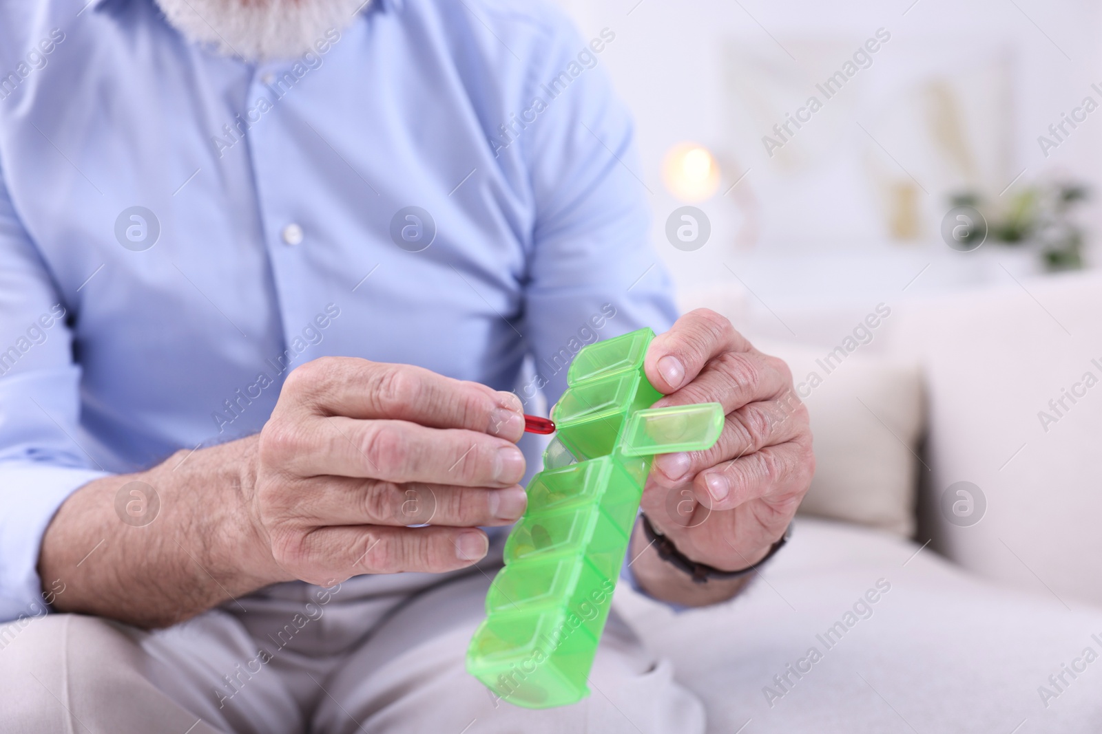 Photo of Senior man with pill and organizer at home, closeup