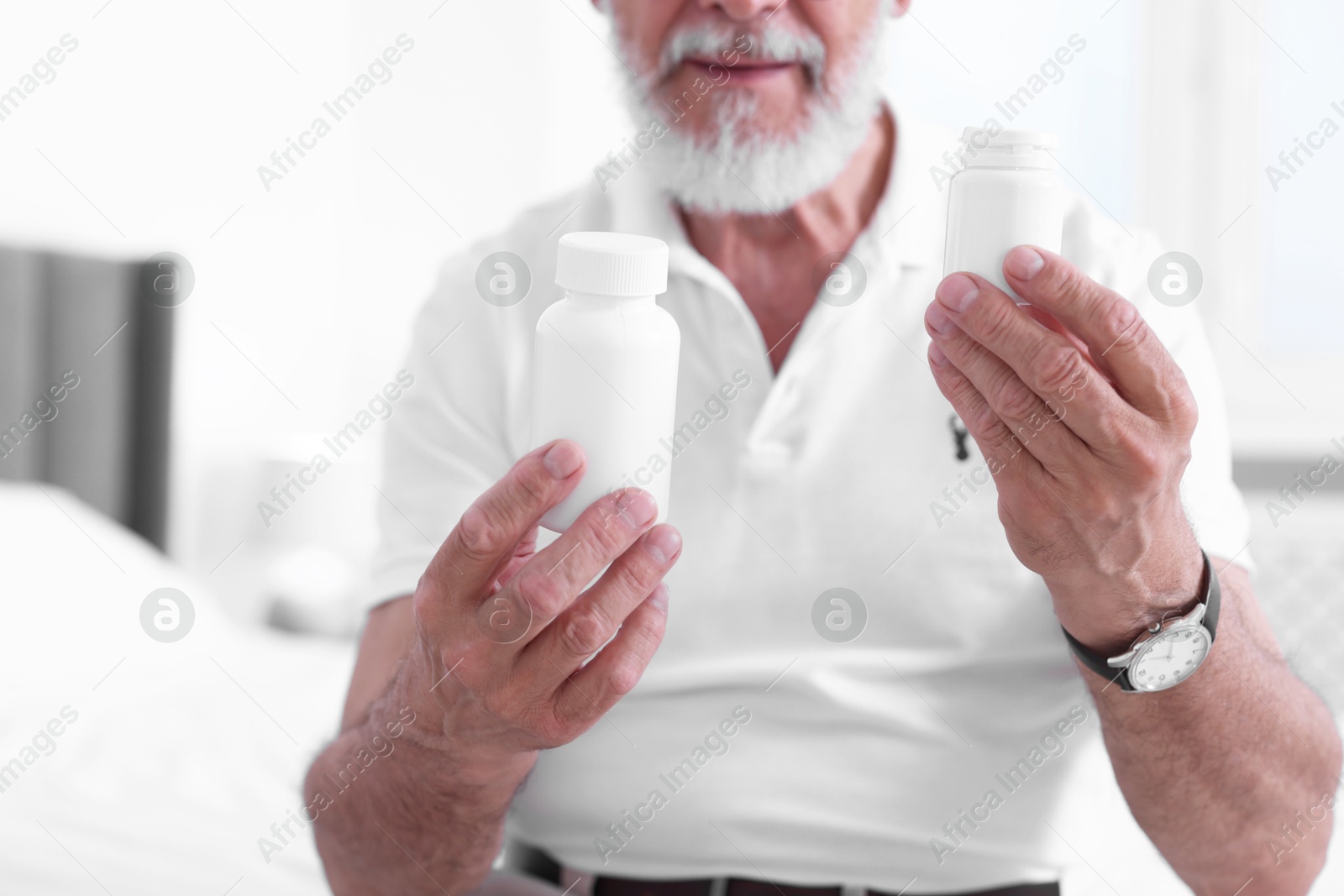 Photo of Senior man with bottles of pills indoors, closeup