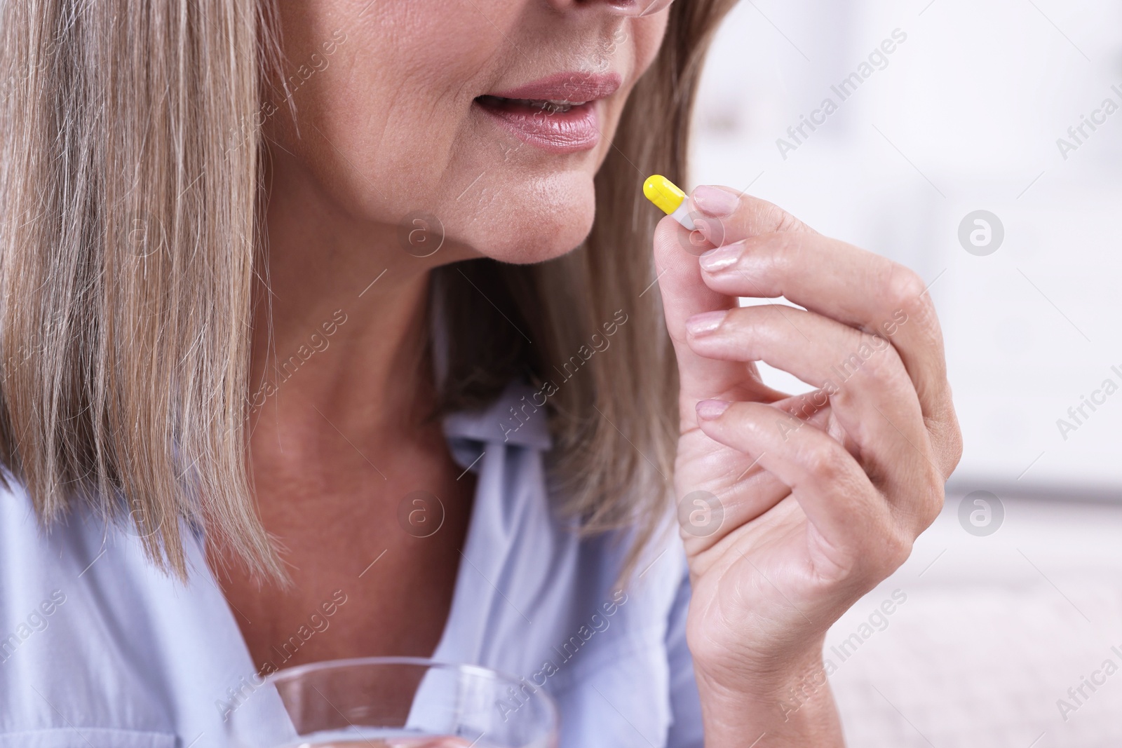 Photo of Senior woman taking pill at home, closeup