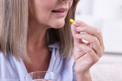 Senior woman taking pill at home, closeup