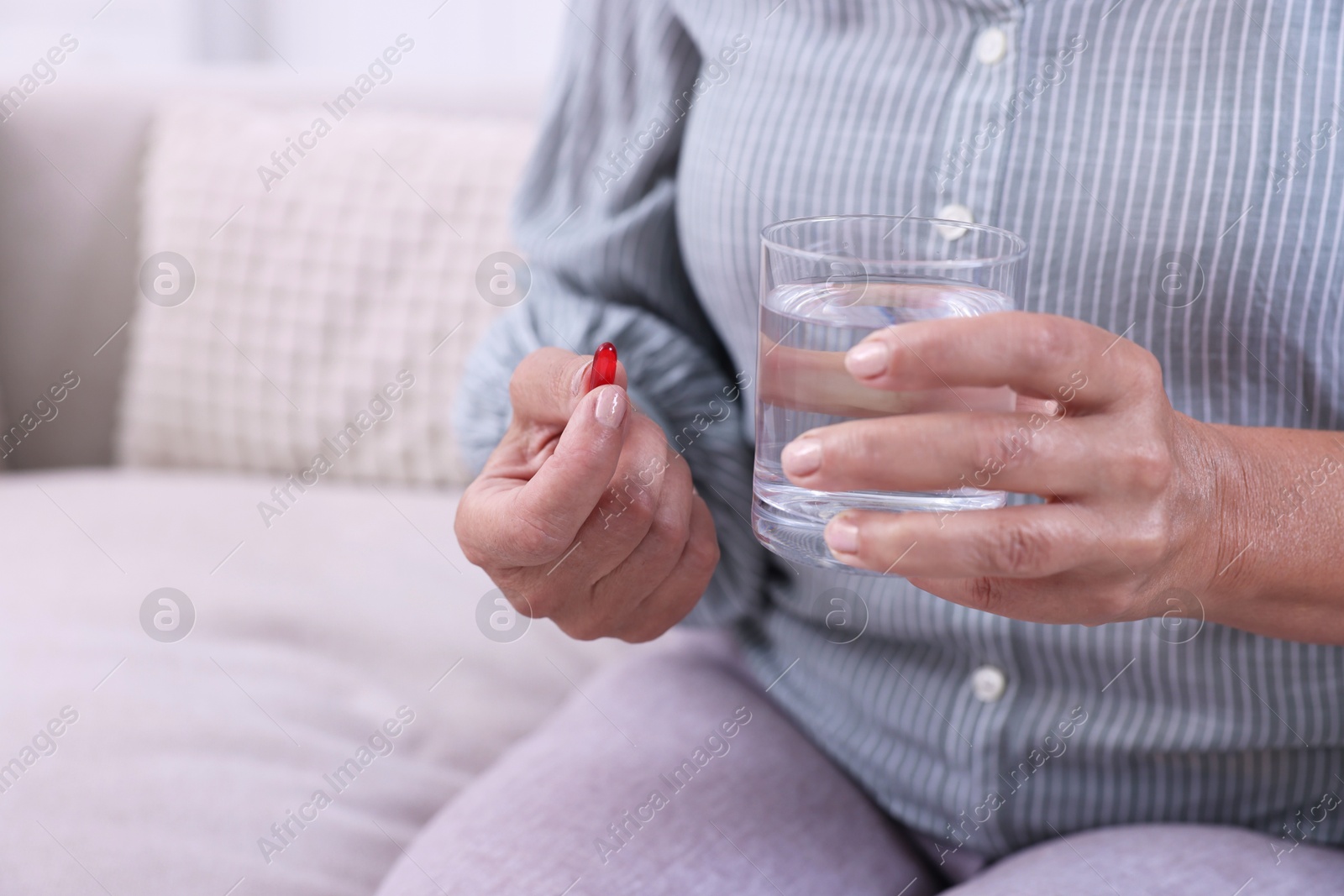 Photo of Senior woman with glass of water and pill at home, closeup. Space for text