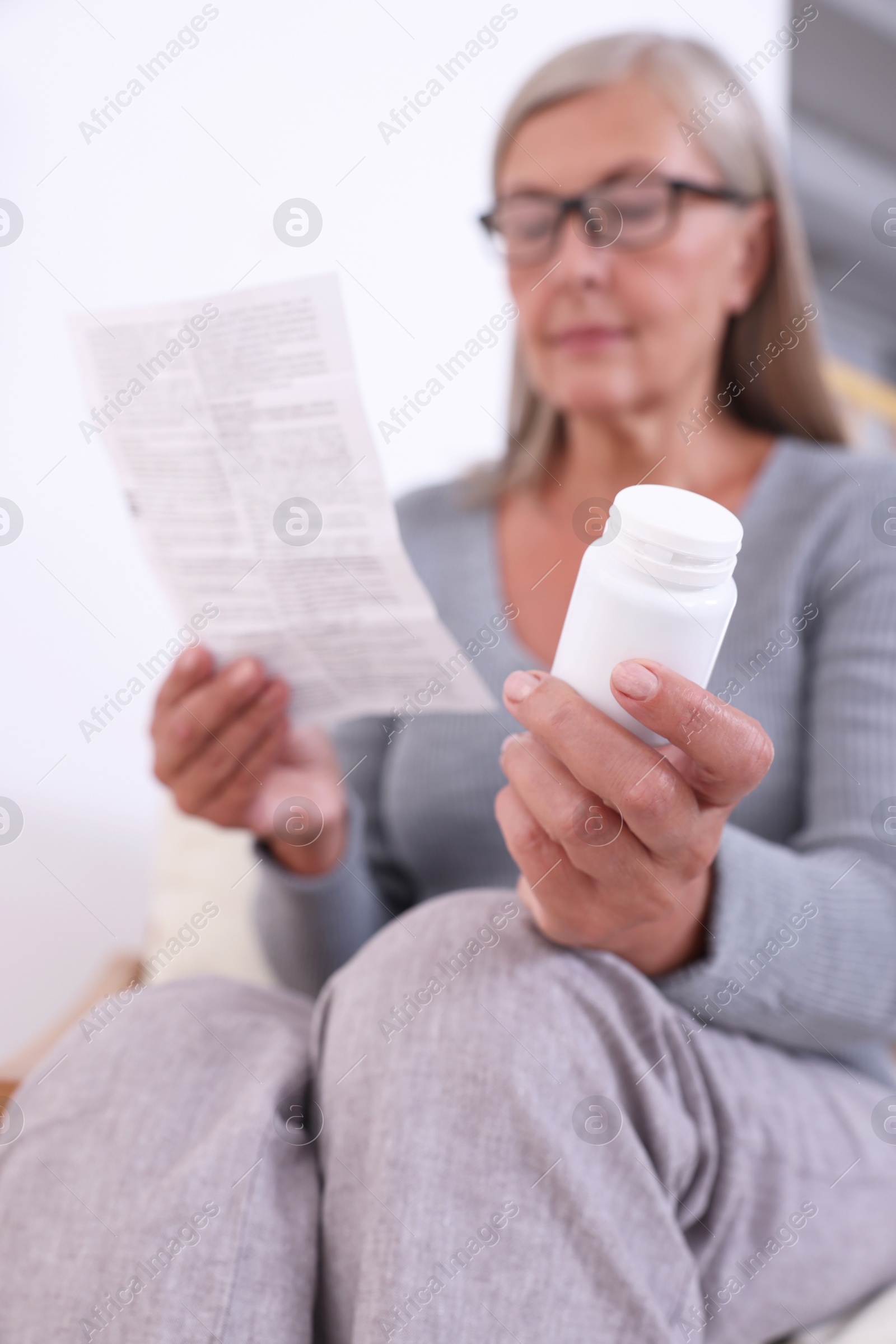 Photo of Senior woman with pills reading medicine instruction at home, selective focus