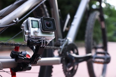 Photo of Modern action camera with mount on bicycle outdoors, closeup