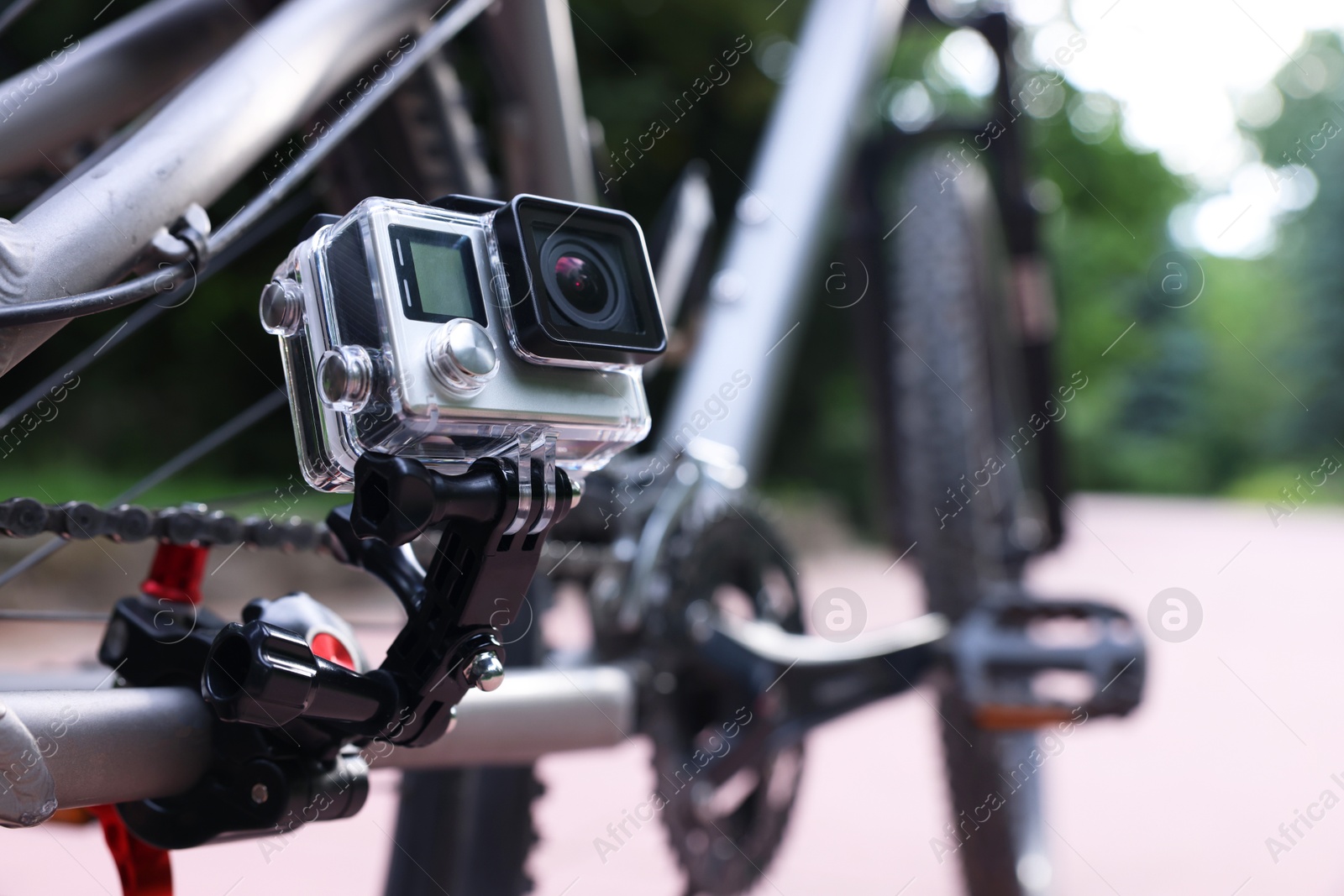 Photo of Modern action camera with mount on bicycle outdoors, closeup