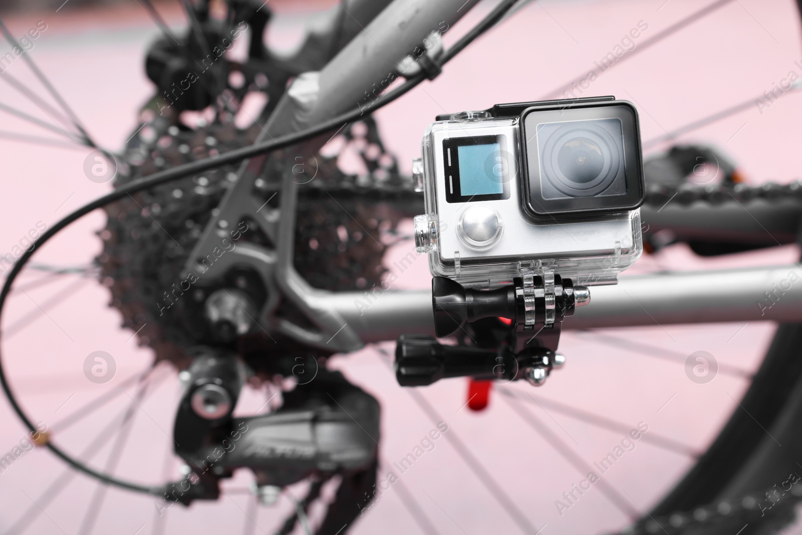 Photo of Modern action camera with mount on bicycle outdoors, space for text