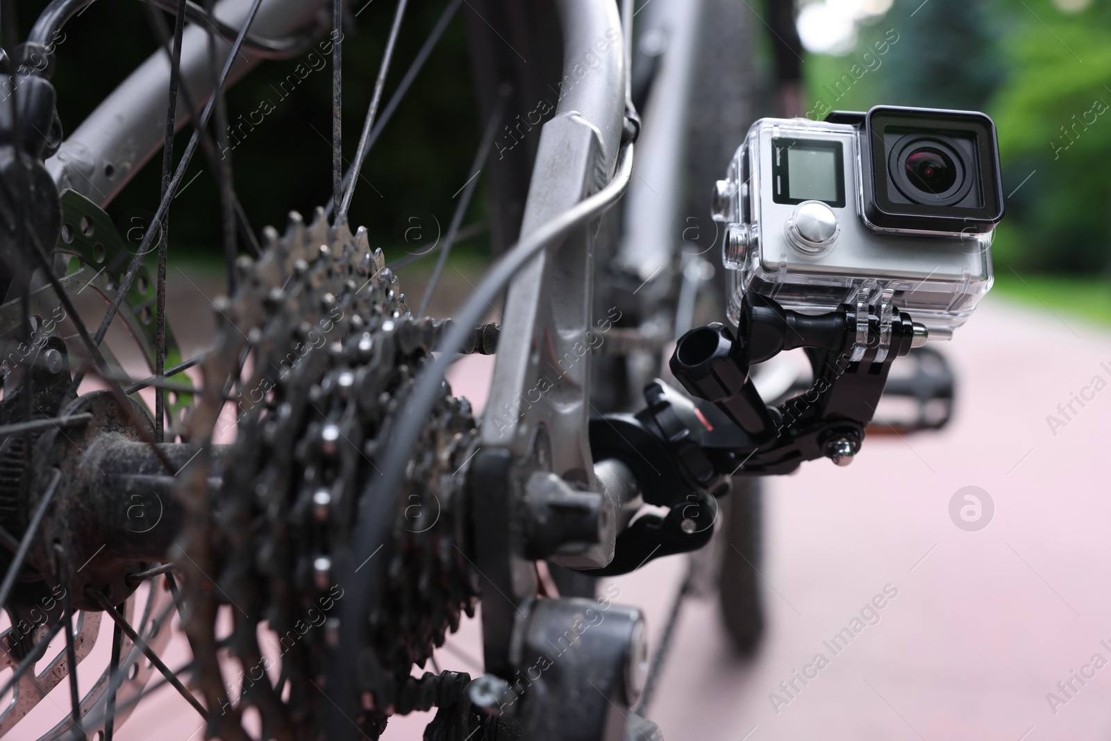 Photo of Modern action camera with mount on bicycle outdoors, closeup