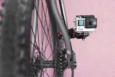 Photo of Modern action camera with mount on bicycle outdoors, closeup