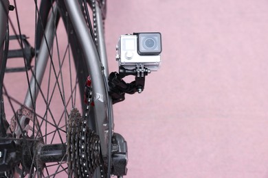 Photo of Modern action camera with mount on bicycle outdoors. Space for text