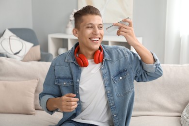 Photo of Young man with smartphone listening to voice message at home