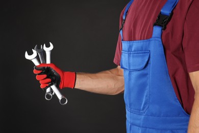 Photo of Auto mechanic with wrenches on black background, closeup