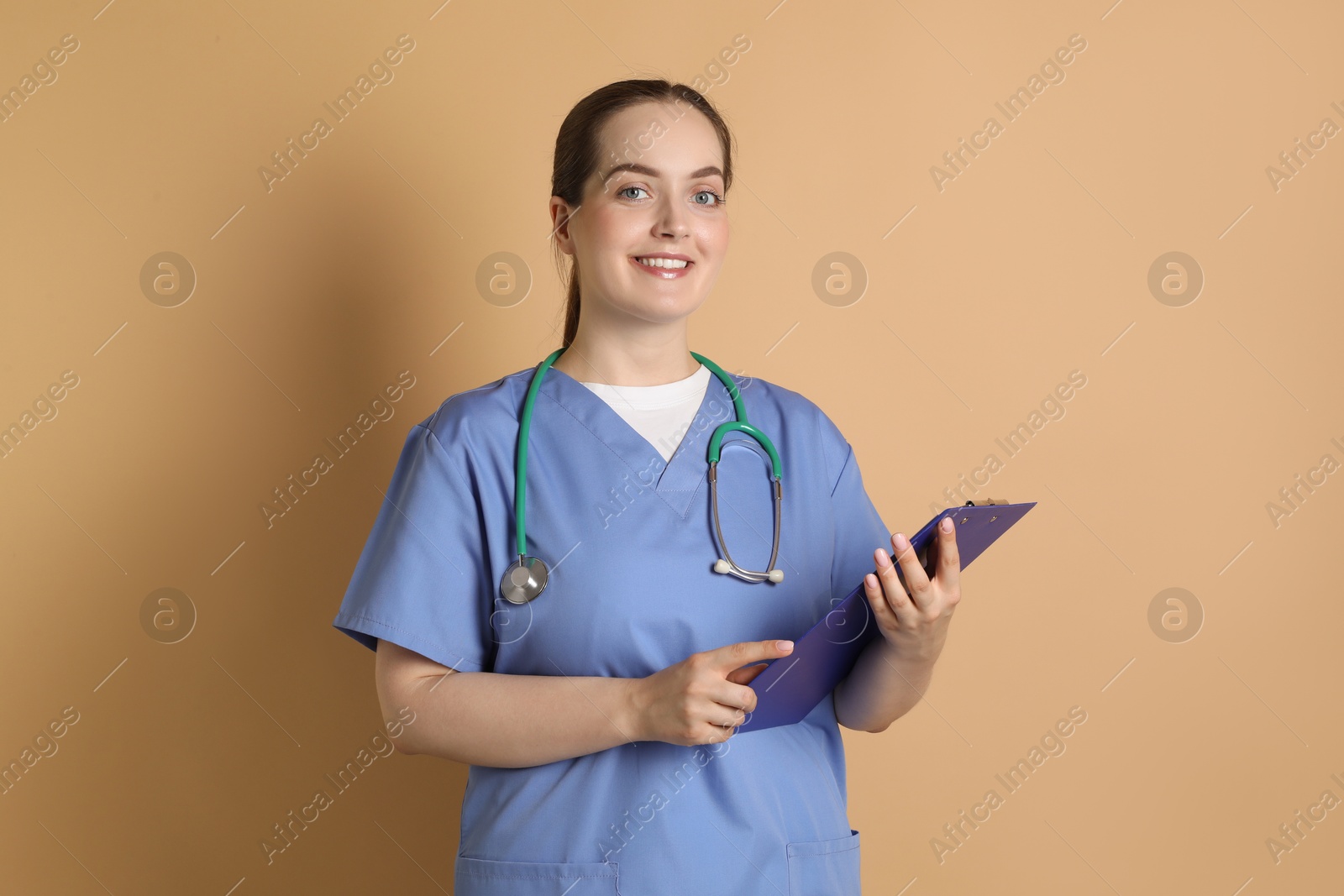 Photo of Portrait of professional nurse with stethoscope and clipboard on dark beige background