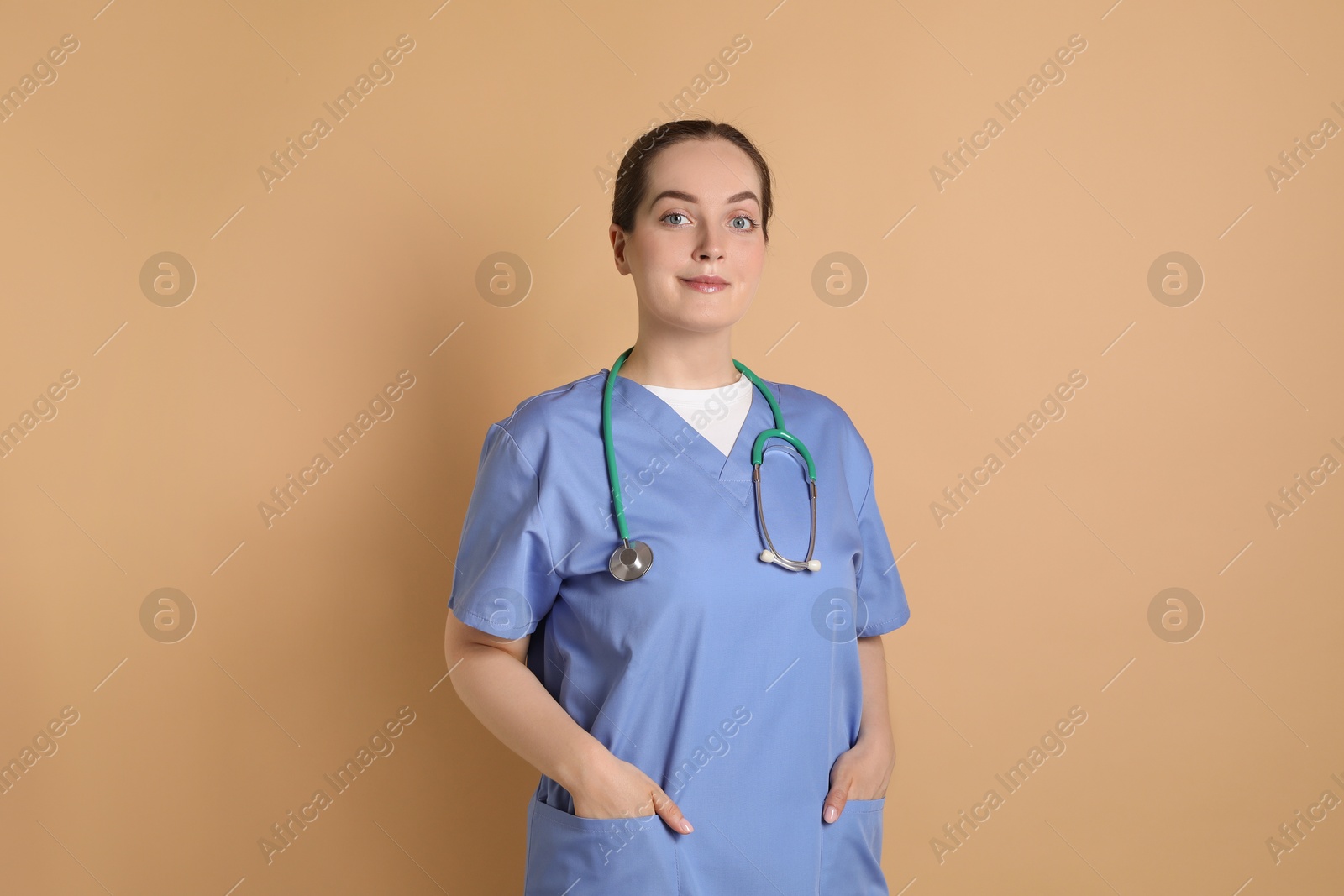 Photo of Portrait of professional nurse with stethoscope on dark beige background