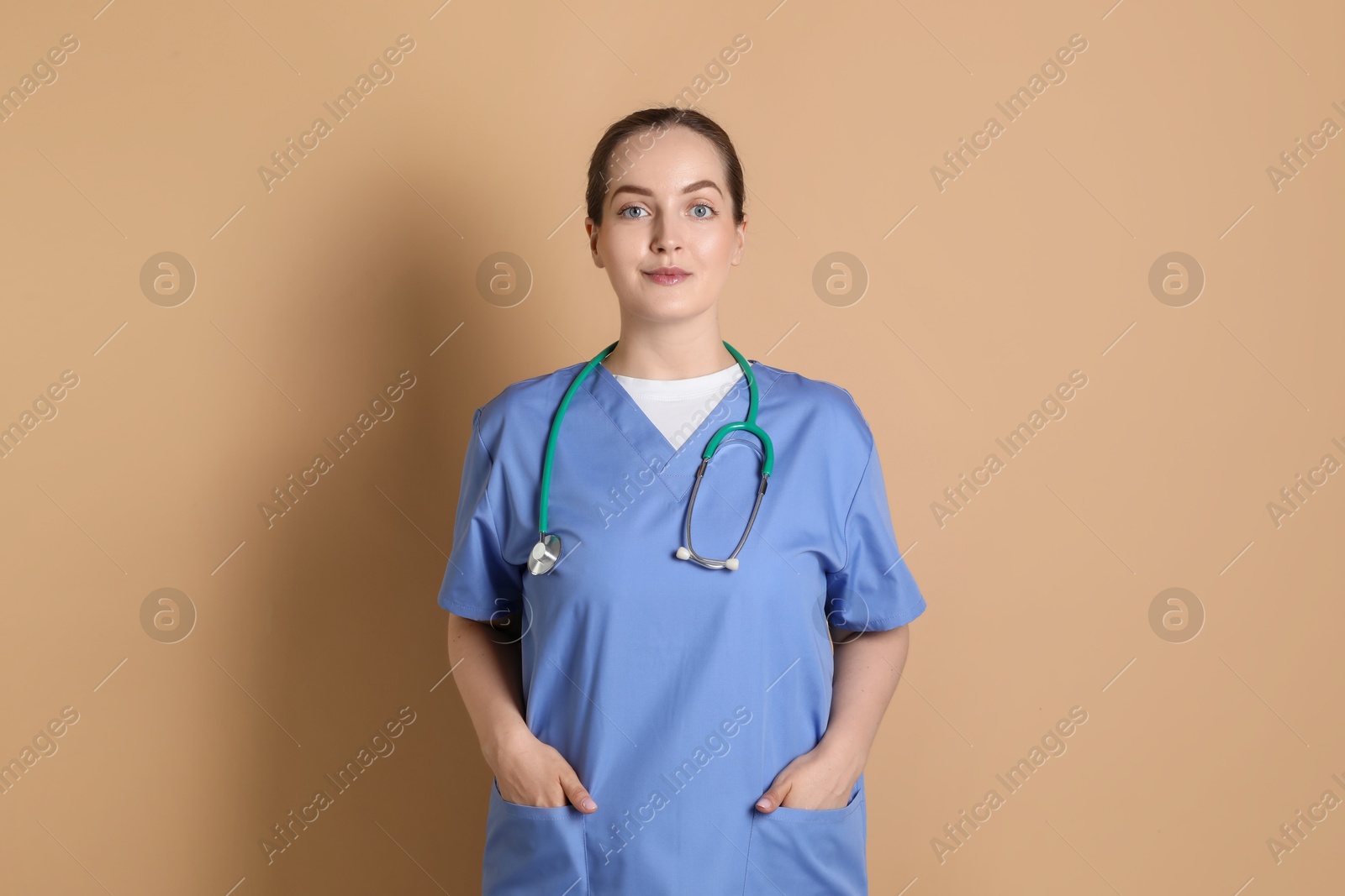 Photo of Portrait of professional nurse with stethoscope on dark beige background