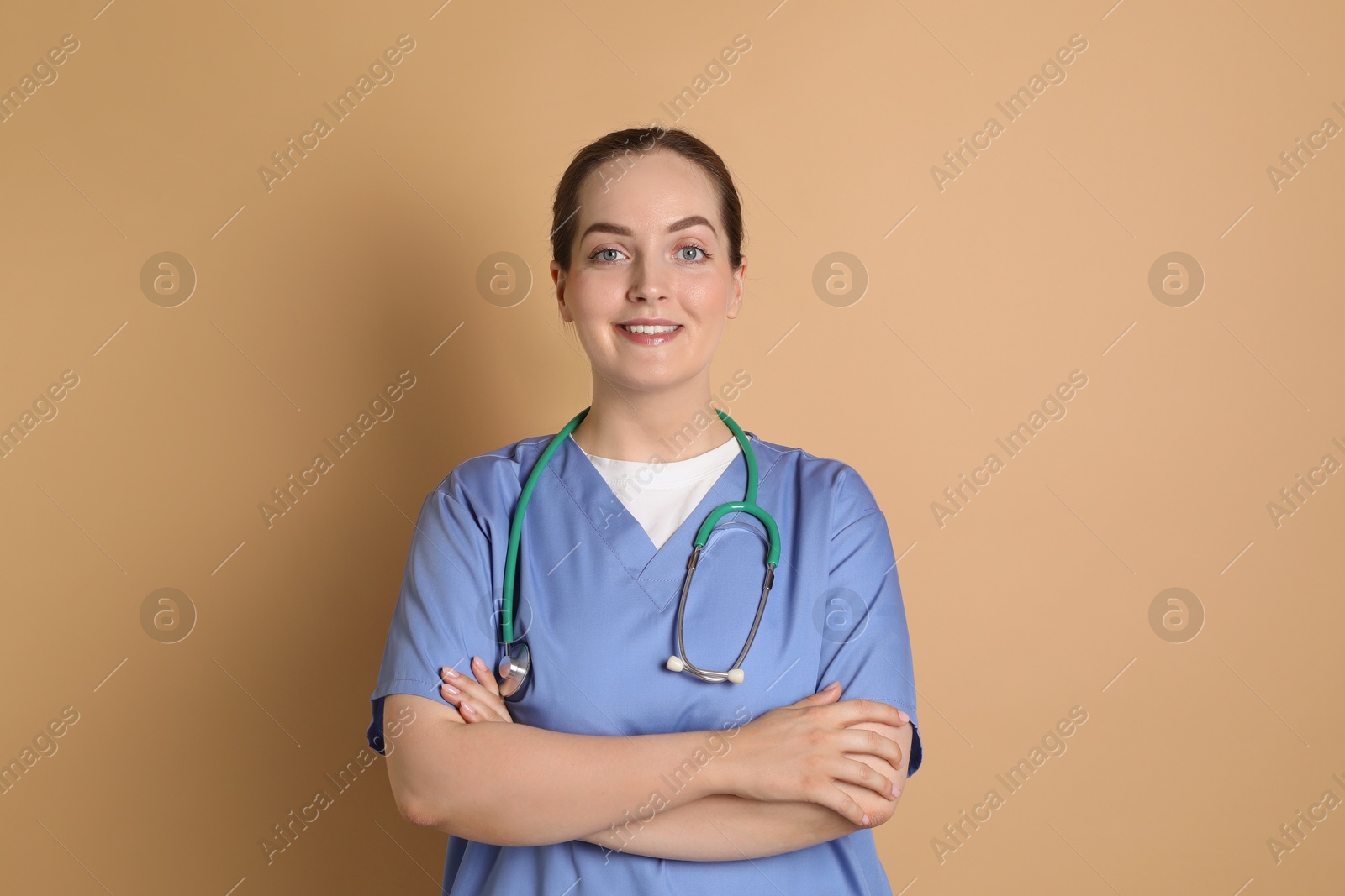 Photo of Portrait of professional nurse with stethoscope on dark beige background