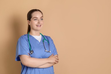 Photo of Portrait of professional nurse with stethoscope on dark beige background. Space for text