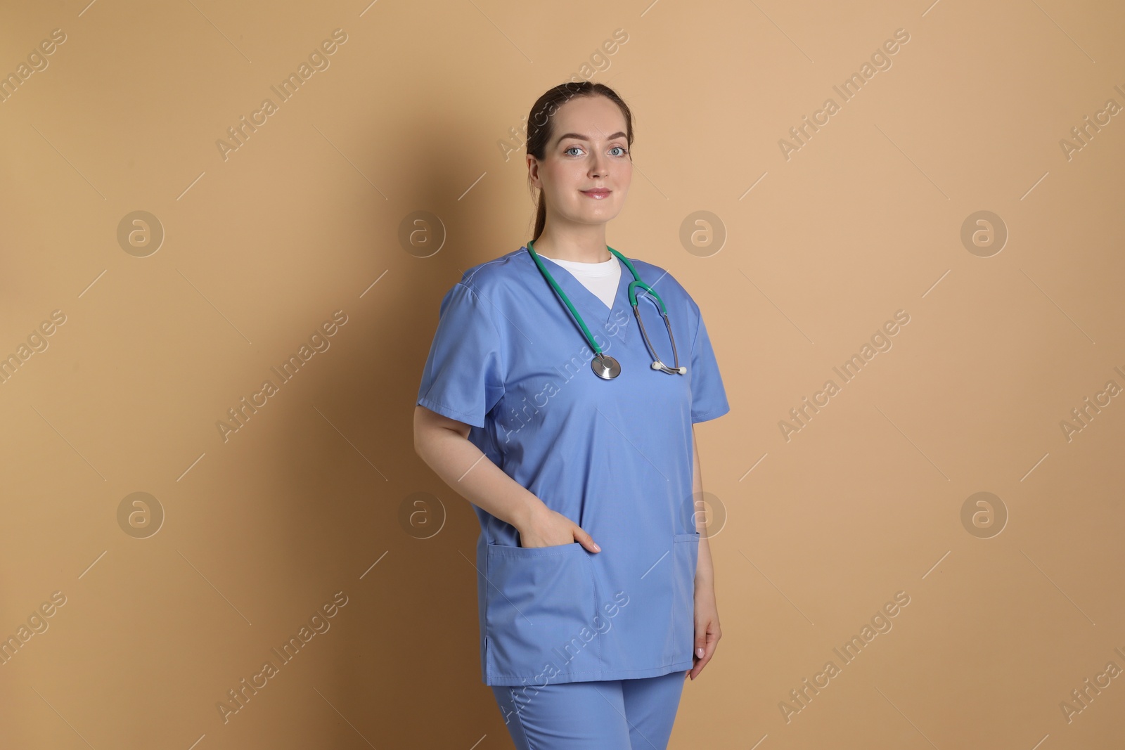 Photo of Portrait of professional nurse with stethoscope on dark beige background