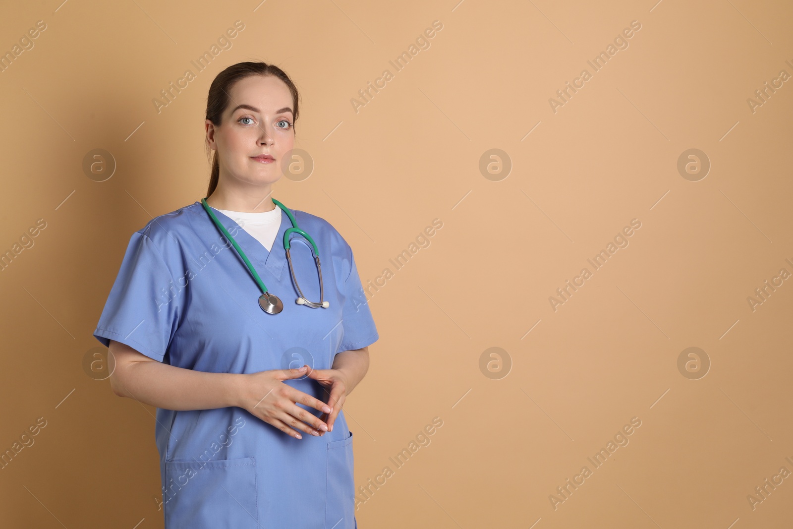 Photo of Portrait of professional nurse with stethoscope on dark beige background. Space for text