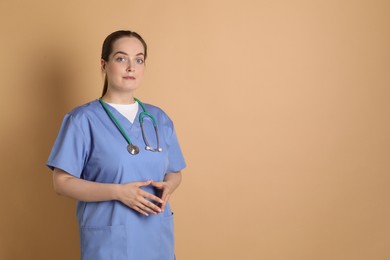 Photo of Portrait of professional nurse with stethoscope on dark beige background. Space for text