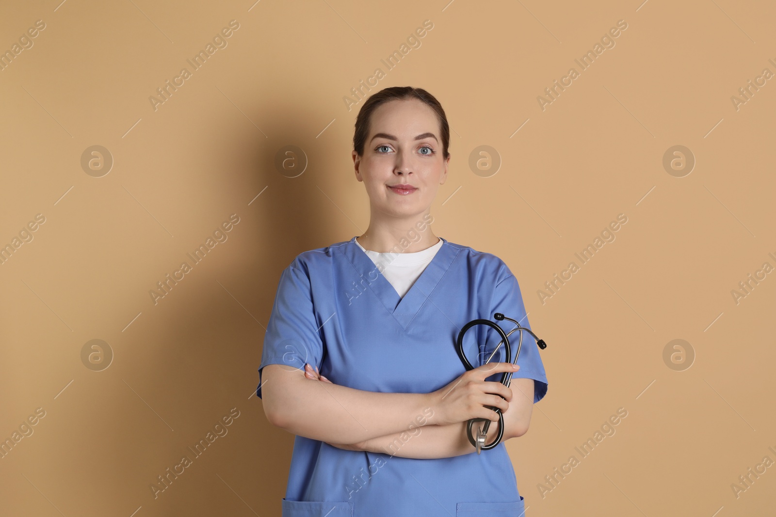 Photo of Portrait of professional nurse with stethoscope on dark beige background