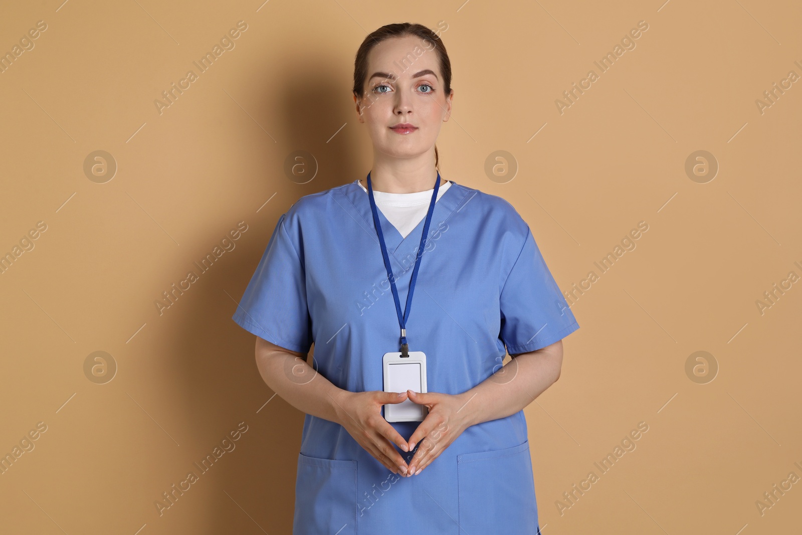 Photo of Professional nurse with badge on dark beige background