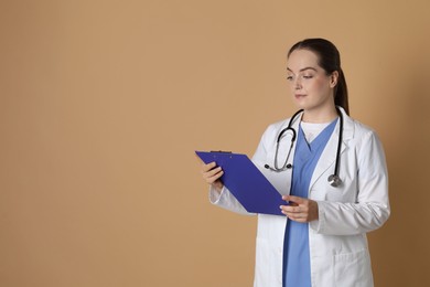 Portrait of professional nurse with clipboard on dark beige background. Space for text