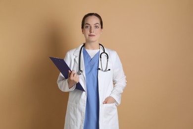 Portrait of professional nurse with clipboard on dark beige background