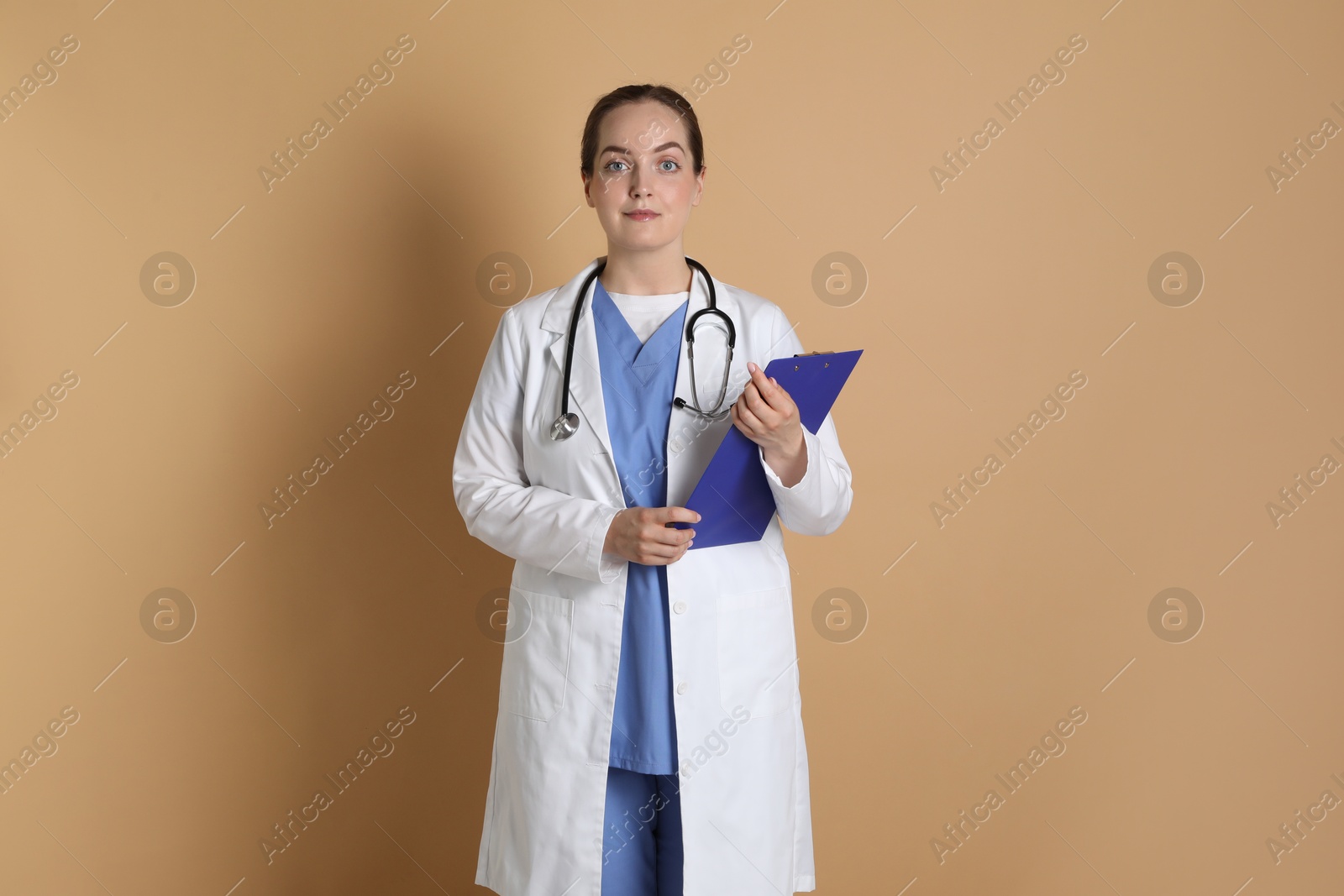 Photo of Portrait of professional nurse with clipboard on dark beige background