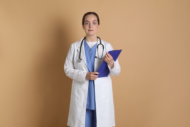 Photo of Portrait of professional nurse with clipboard on dark beige background