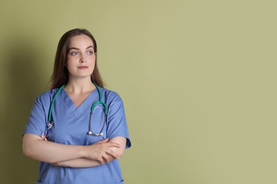 Professional nurse with stethoscope on pale green background. Space for text