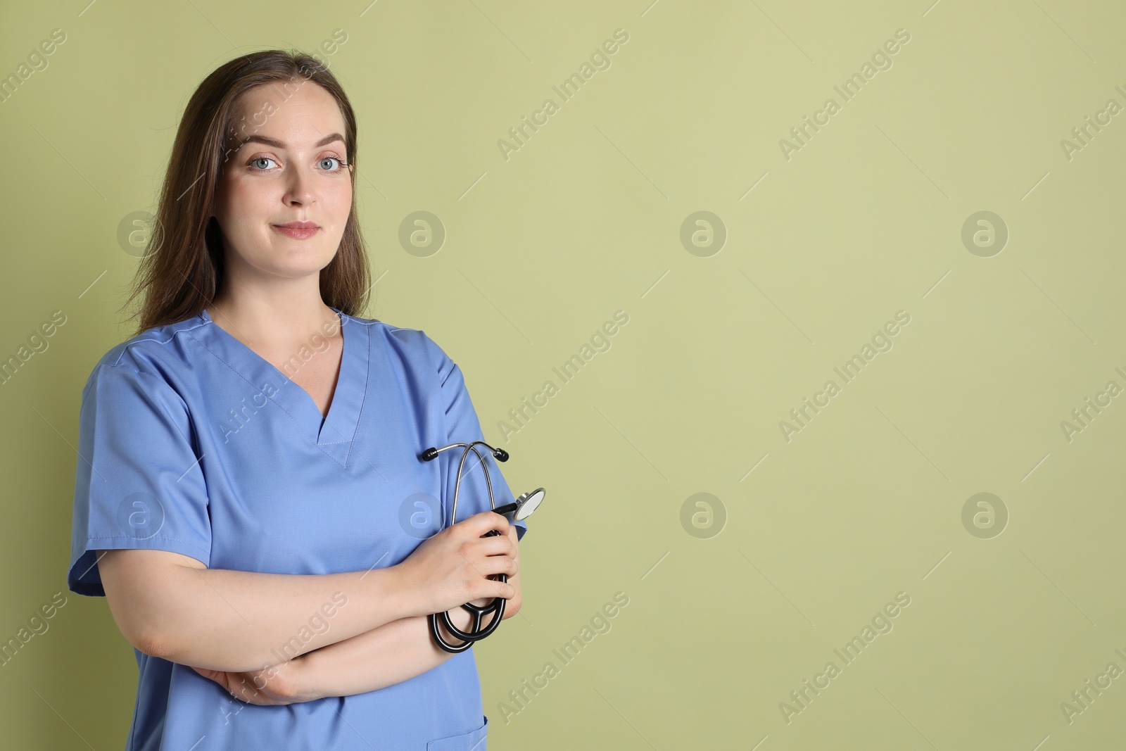 Photo of Professional nurse with stethoscope on pale green background. Space for text