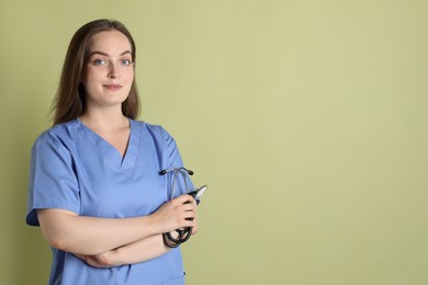 Professional nurse with stethoscope on pale green background. Space for text