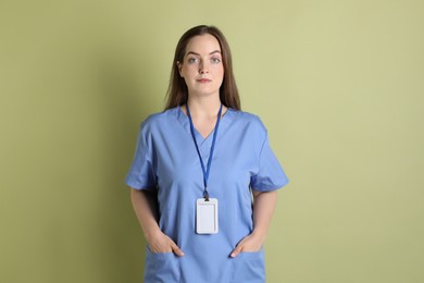 Photo of Professional nurse with badge on pale green background