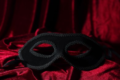 Photo of One beautiful carnival mask on red fabric, closeup