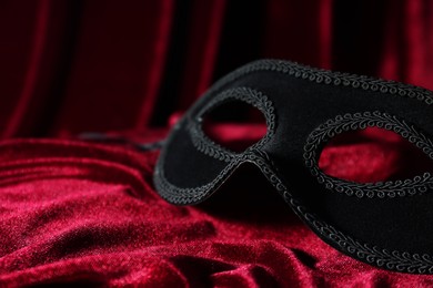 One beautiful carnival mask on red fabric, closeup. Space for text