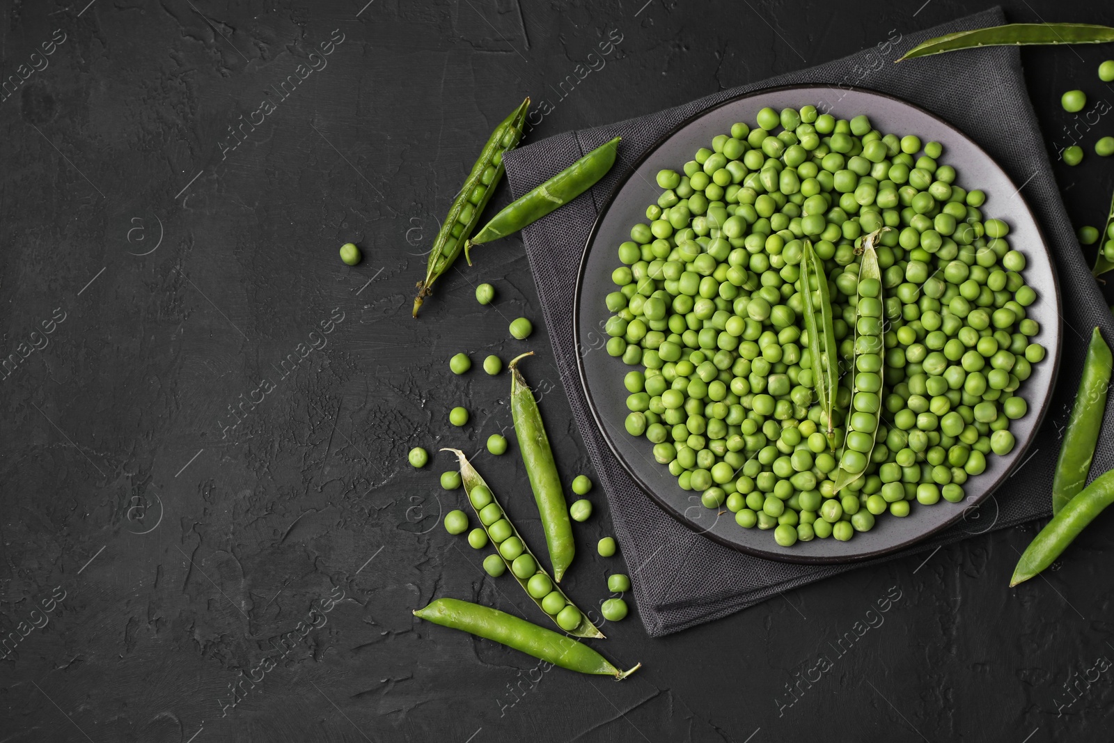 Photo of Fresh green peas and pods on black table, flat lay. Space for text