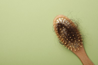 One brush with lost hair on light olive background, top view. Space for text