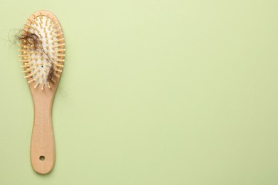 One brush with lost hair on light olive background, top view. Space for text