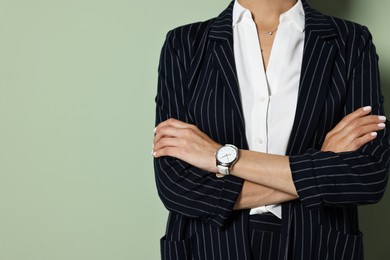 Woman in black striped suit on green background, closeup. Space for text