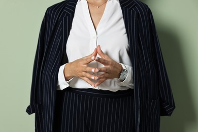 Woman in black striped suit on green background, closeup