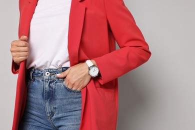 Woman in red jacket and jeans on gray background, closeup. Space for text