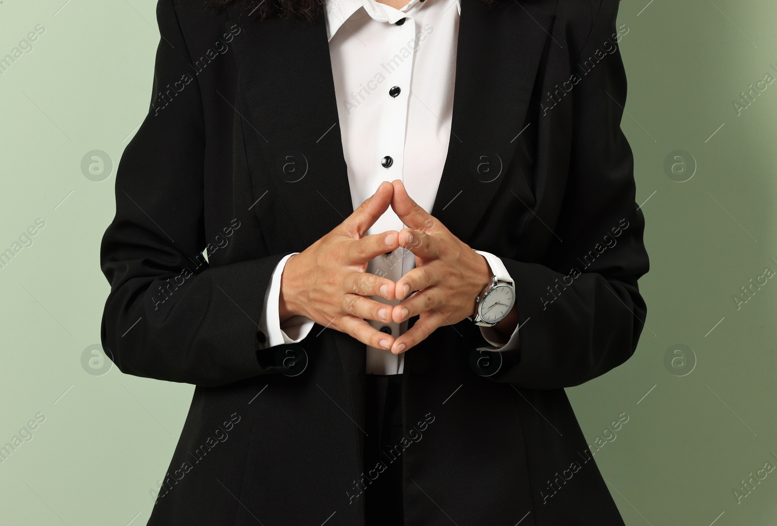 Photo of Woman in stylish black suit on light olive background, closeup