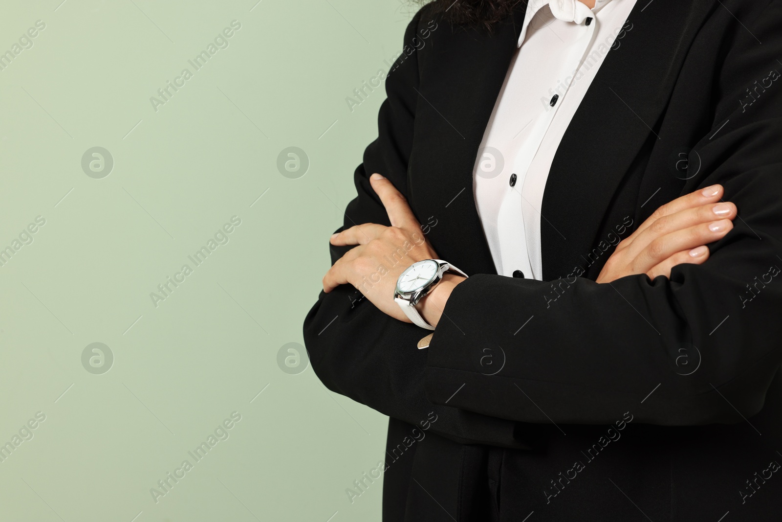 Photo of Woman in stylish black suit on light olive background, closeup. Space for text