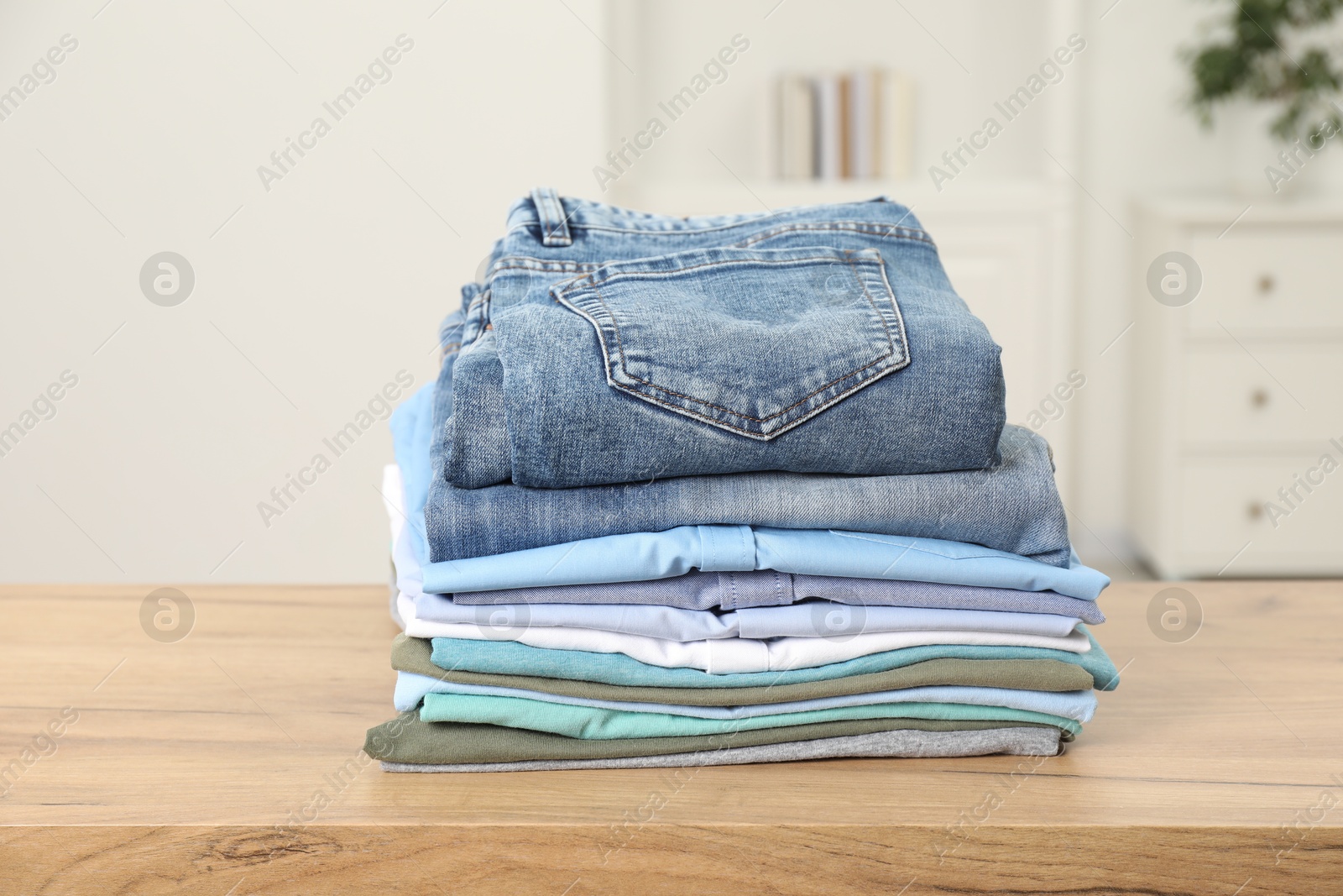 Photo of Stack of clothes on wooden table indoors