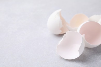 Photo of Broken eggshells on grey textured table, closeup. Space for text