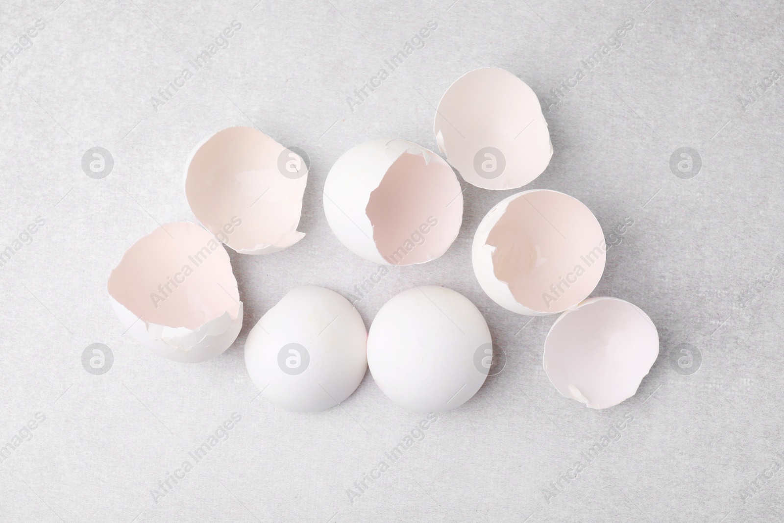 Photo of Broken eggshells on grey textured table, top view