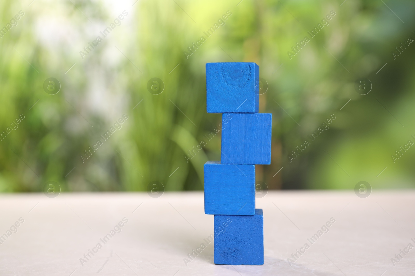 Photo of Blank blue cubes on light grey table outdoors, space for text