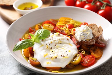 Photo of Delicious fresh burrata salad in bowl on table, closeup