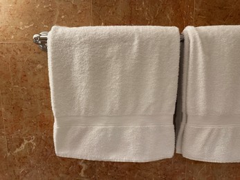 Soft terry towels hanging on tiled wall in hotel bathroom