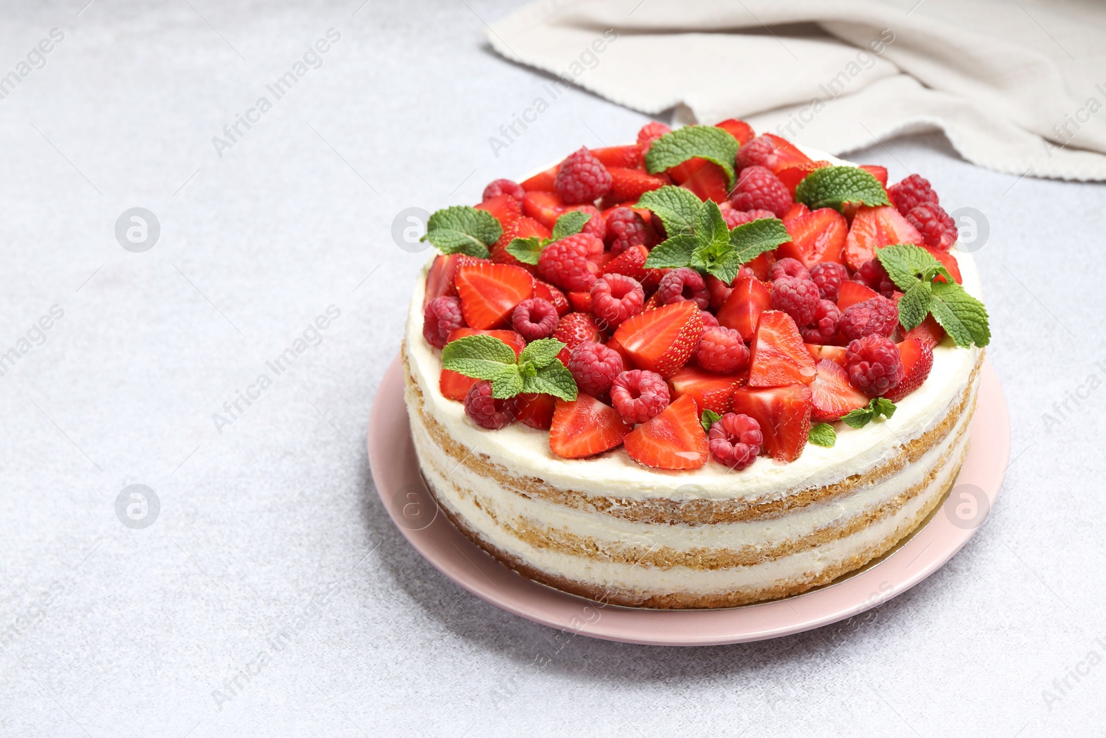 Photo of Tasty sponge cake with fresh berries and mint on light gray table, closeup. Space for text